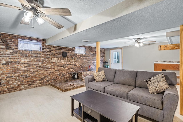 living room featuring ceiling fan, light hardwood / wood-style floors, a textured ceiling, brick wall, and a wood stove