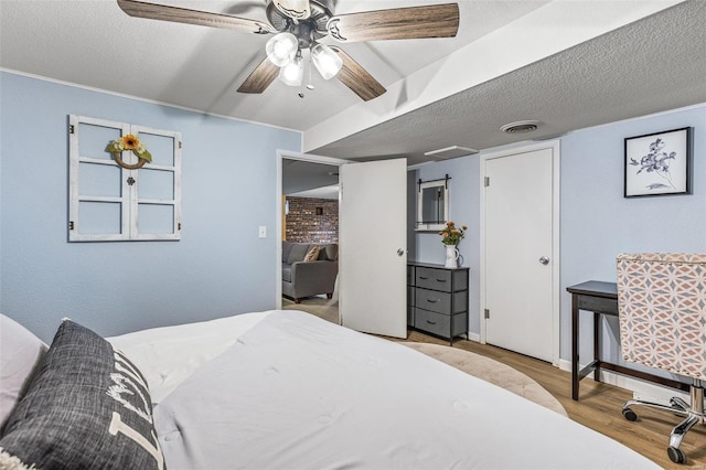 bedroom featuring ceiling fan, light wood-type flooring, and a textured ceiling