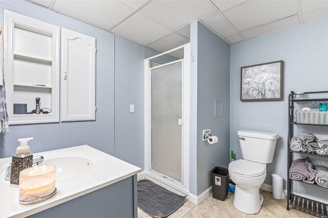 bathroom with vanity, a shower with shower door, toilet, and a paneled ceiling