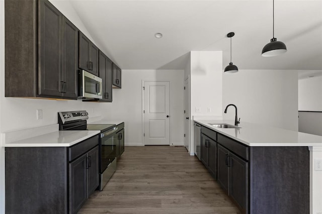 kitchen with sink, appliances with stainless steel finishes, dark hardwood / wood-style floors, dark brown cabinetry, and decorative light fixtures