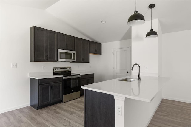 kitchen with pendant lighting, sink, lofted ceiling, appliances with stainless steel finishes, and kitchen peninsula