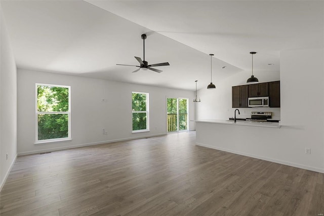 unfurnished living room with vaulted ceiling, sink, ceiling fan, and light hardwood / wood-style floors