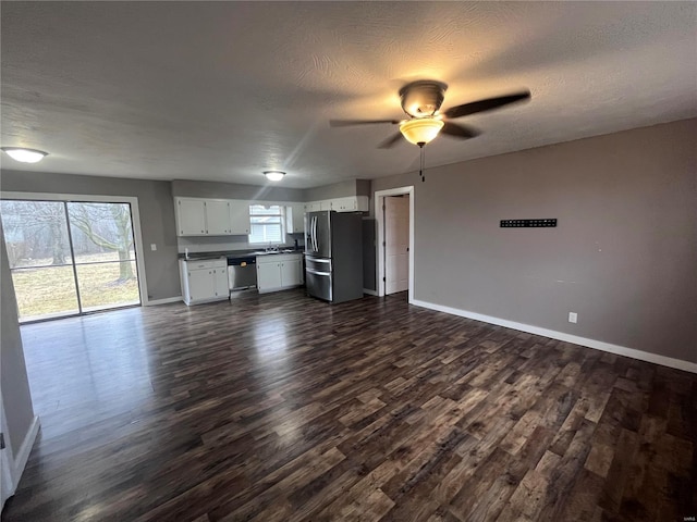 unfurnished living room featuring ceiling fan, dark wood-type flooring, and a textured ceiling