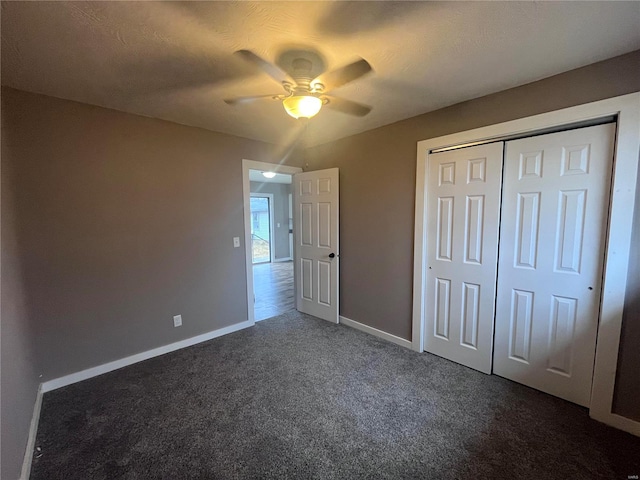 unfurnished bedroom with ceiling fan, a textured ceiling, dark carpet, and a closet