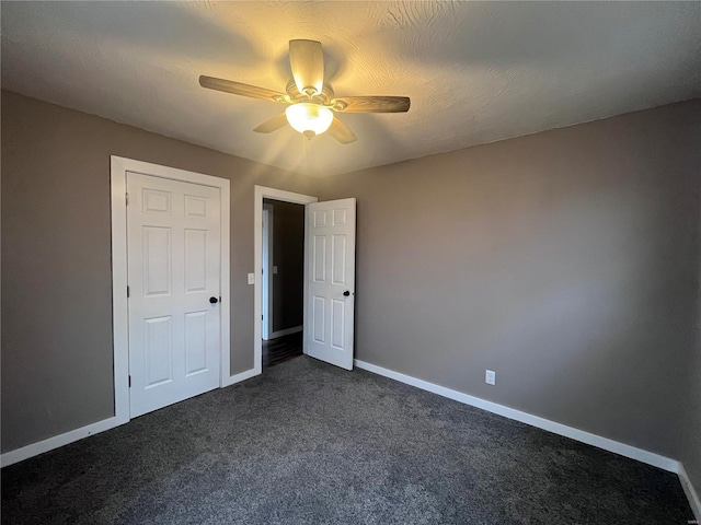 unfurnished bedroom with ceiling fan and dark colored carpet