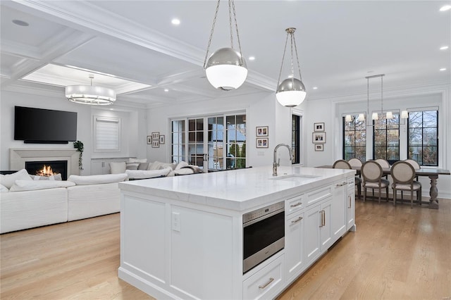 kitchen with pendant lighting, open floor plan, a kitchen island with sink, and a sink