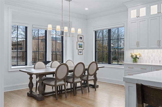 dining space with light wood finished floors, baseboards, and ornamental molding