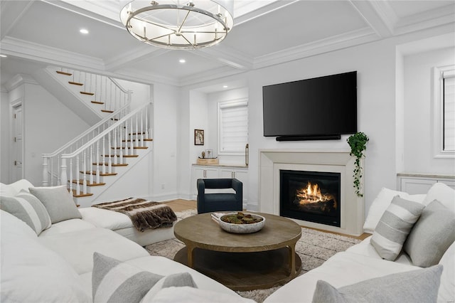 living area with a glass covered fireplace, beam ceiling, coffered ceiling, and stairs