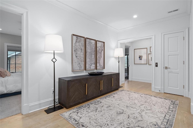 hallway with recessed lighting, visible vents, baseboards, light wood-type flooring, and crown molding