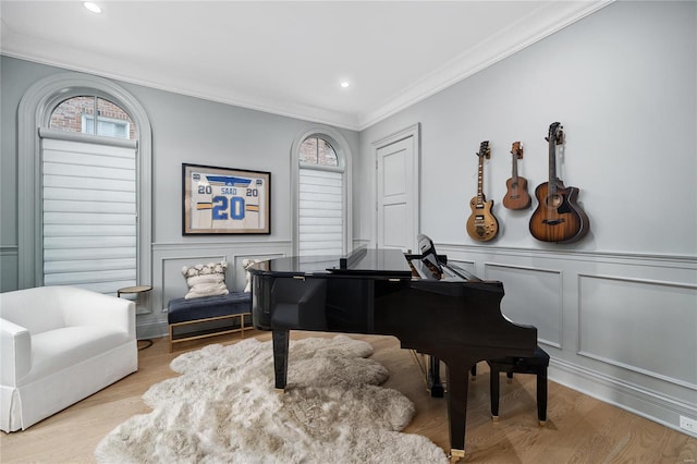 living area featuring ornamental molding, light wood-type flooring, plenty of natural light, and a decorative wall