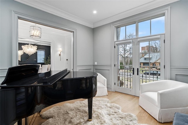 sitting room featuring french doors, a decorative wall, a wealth of natural light, and crown molding