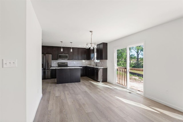 kitchen featuring sink, a center island, pendant lighting, stainless steel appliances, and decorative backsplash