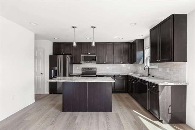 kitchen with sink, hanging light fixtures, light hardwood / wood-style floors, black appliances, and a kitchen island