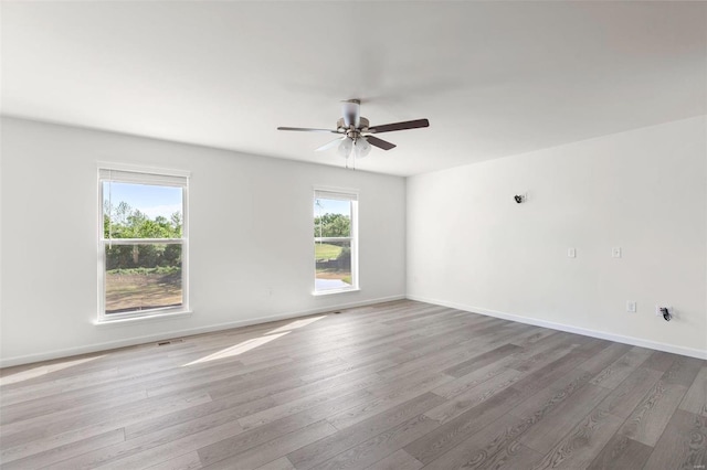 spare room featuring plenty of natural light, ceiling fan, and light wood-type flooring