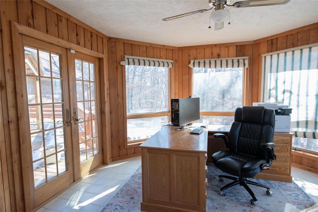 home office featuring a healthy amount of sunlight, a textured ceiling, and wood walls