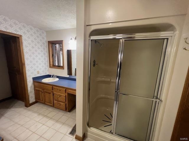 bathroom with vanity, a textured ceiling, and a shower with shower door