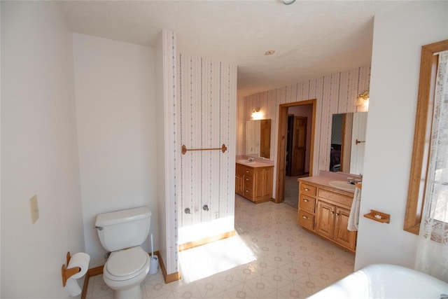 bathroom featuring vanity, a washtub, and toilet