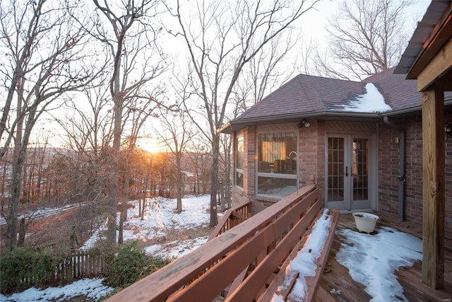 snow covered deck featuring french doors and fence