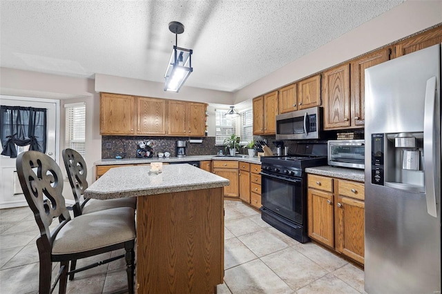 kitchen featuring appliances with stainless steel finishes, a breakfast bar, pendant lighting, sink, and a center island