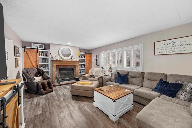 living room featuring a fireplace, a barn door, hardwood / wood-style floors, and a textured ceiling