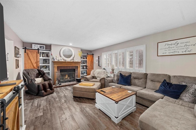 living room with wood-type flooring, a barn door, a fireplace, and a textured ceiling