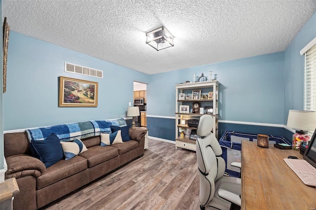 home office with wood-type flooring and a textured ceiling