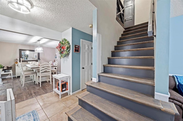 stairs with tile patterned flooring and a textured ceiling