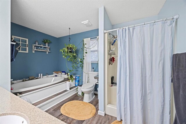 full bathroom with plus walk in shower, hardwood / wood-style flooring, vanity, toilet, and a textured ceiling