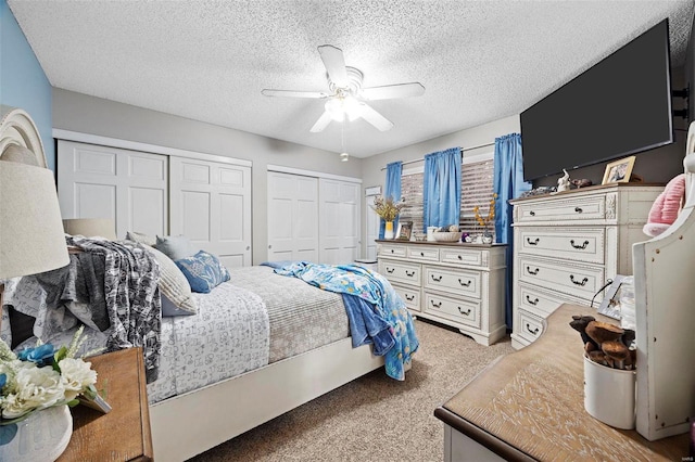 bedroom with multiple closets, ceiling fan, light colored carpet, and a textured ceiling