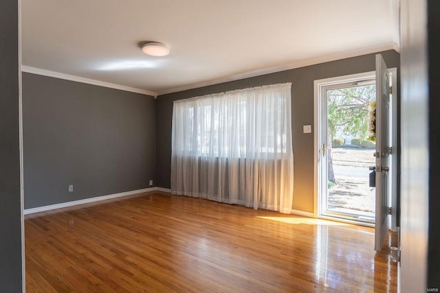 spare room with ornamental molding, baseboards, and wood finished floors