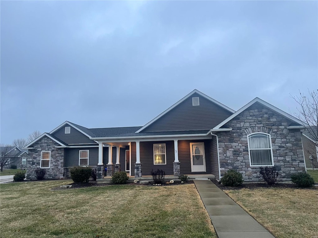 craftsman inspired home featuring a porch and a front lawn