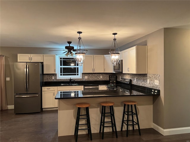 kitchen with sink, stainless steel appliances, a kitchen bar, decorative light fixtures, and kitchen peninsula