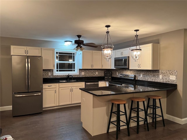 kitchen with appliances with stainless steel finishes, white cabinets, and kitchen peninsula