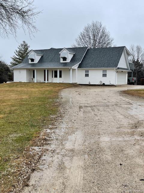 view of front of home featuring a front lawn, an attached garage, driveway, and a shingled roof