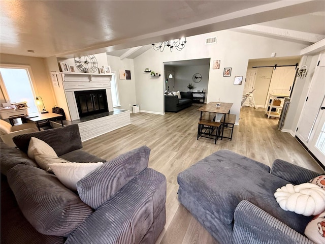 living room with vaulted ceiling with beams, light hardwood / wood-style flooring, and a barn door