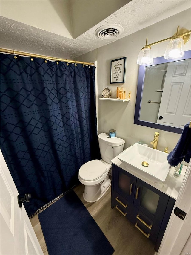 bathroom featuring hardwood / wood-style flooring, vanity, a textured ceiling, curtained shower, and toilet