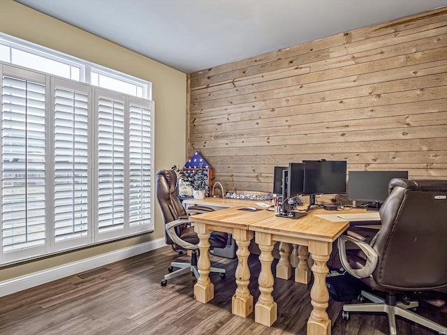 home office with wood walls, visible vents, baseboards, and wood finished floors