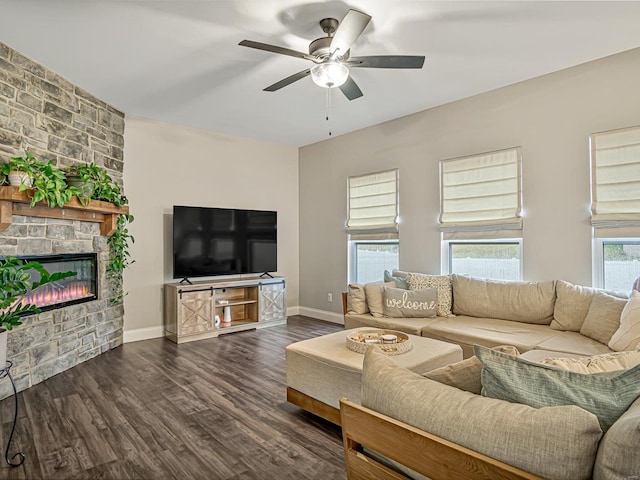 living area featuring a ceiling fan, dark wood-style flooring, a fireplace, and baseboards