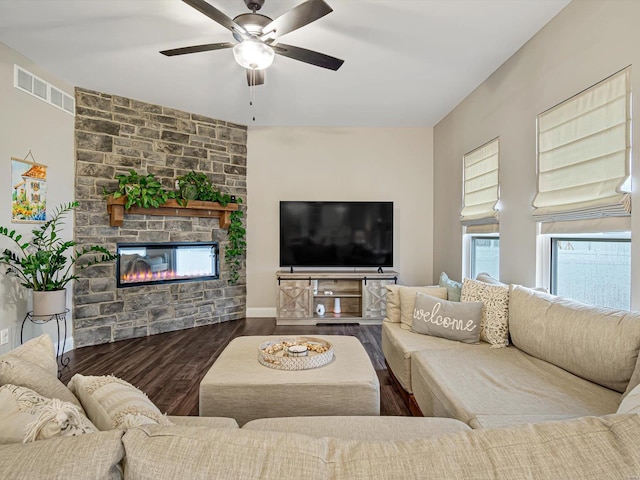 living room featuring baseboards, visible vents, a ceiling fan, wood finished floors, and a fireplace