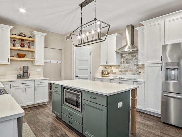 kitchen with stainless steel appliances, light countertops, dark wood-type flooring, white cabinets, and wall chimney range hood