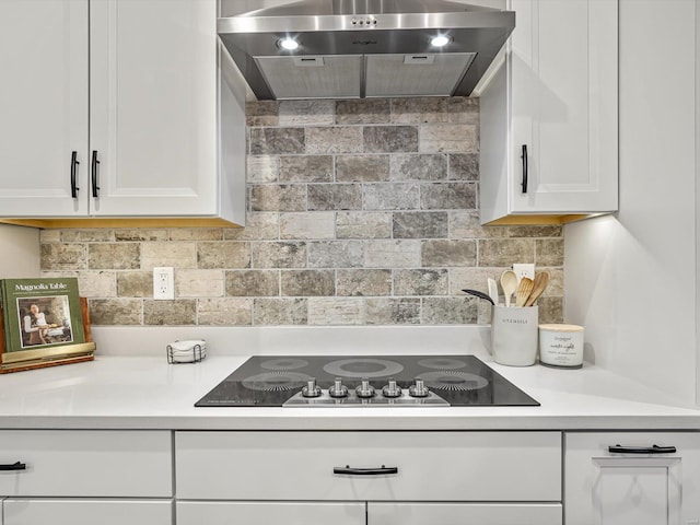 kitchen featuring tasteful backsplash, white cabinets, range hood, black electric cooktop, and light countertops