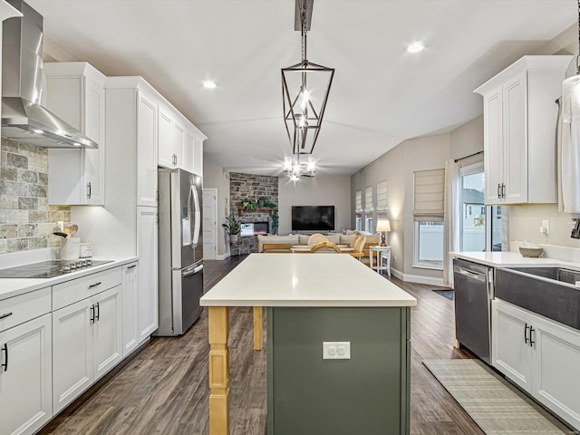 kitchen with dark wood-style floors, a fireplace, stainless steel appliances, open floor plan, and wall chimney exhaust hood