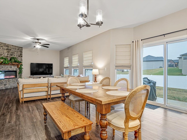 dining room with dark wood-style floors, visible vents, a fireplace, and ceiling fan with notable chandelier