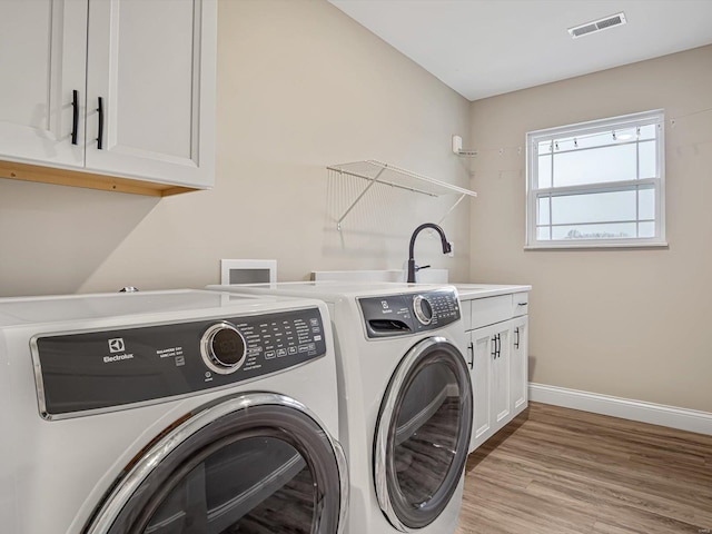 laundry room featuring light wood-style flooring, visible vents, baseboards, cabinet space, and washer and clothes dryer