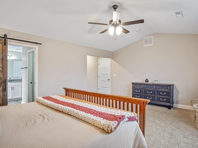 bedroom featuring light carpet, a barn door, vaulted ceiling, and visible vents