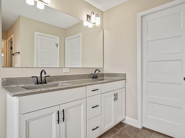 bathroom with double vanity, tile patterned flooring, baseboards, and a sink