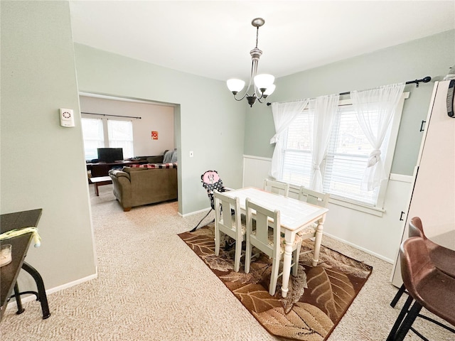 carpeted dining space featuring a chandelier