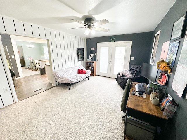 living room with ceiling fan with notable chandelier, light colored carpet, and french doors