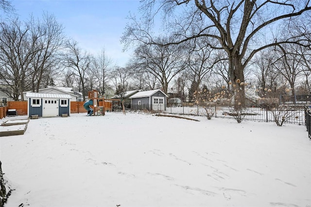 yard covered in snow featuring a playground and a storage shed