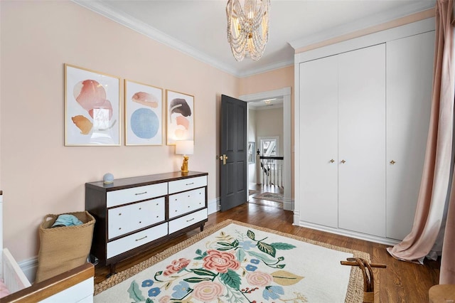 bedroom with a closet, crown molding, dark hardwood / wood-style floors, and an inviting chandelier